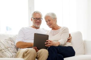 Internet Banner - Senior couple looking at a tablet while sitting on the couch together