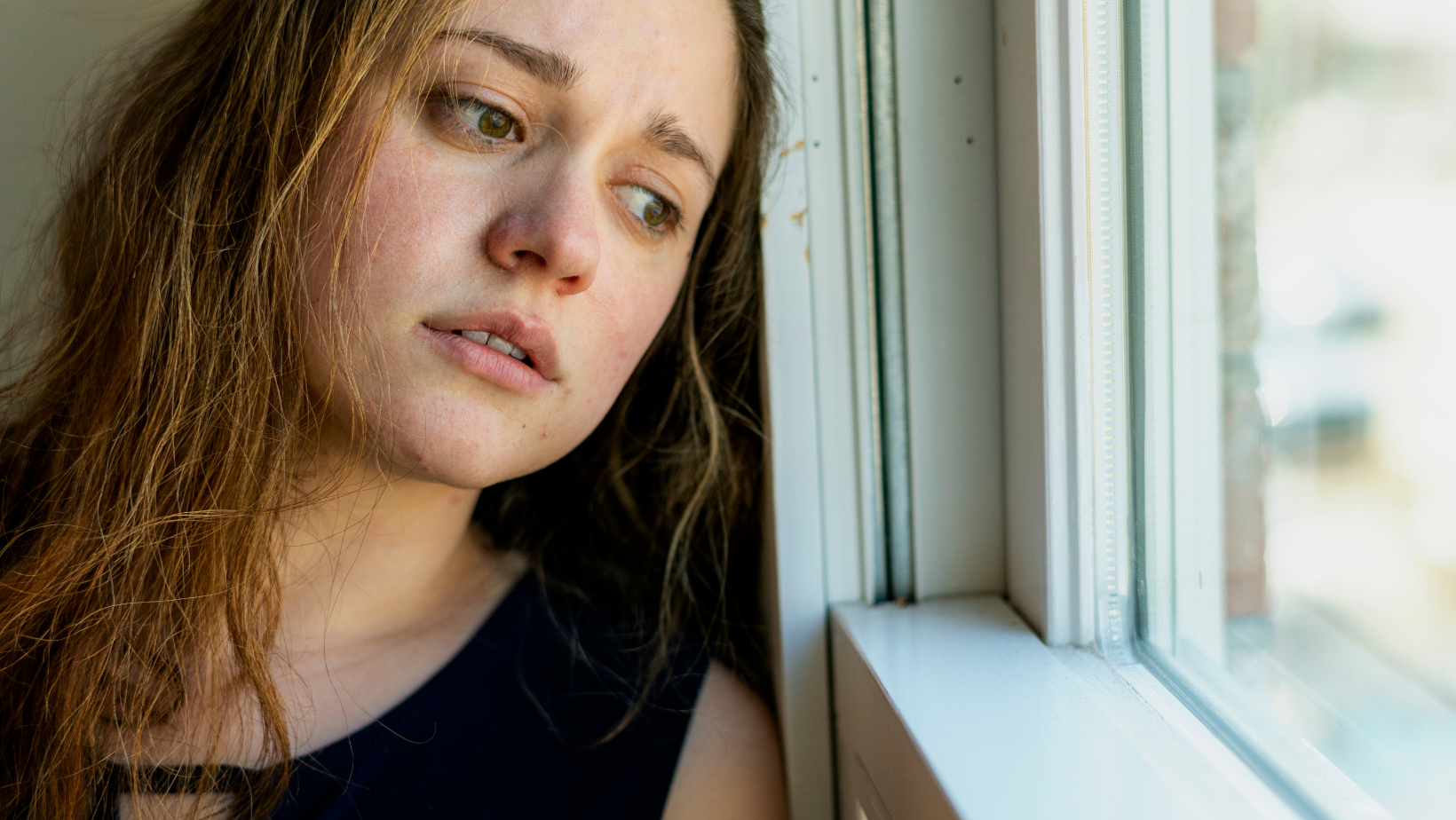 Close up of a stressed and unhappy young Australian woman looking out the window