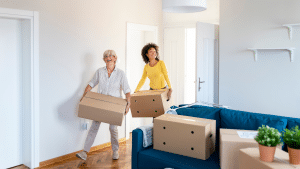 Two women moving house carrying boxes