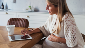 Pregnant woman looking at health insurance options on tablet