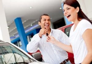Car Loans Banner - Couple happily smiling and holding car keys after buying a new car