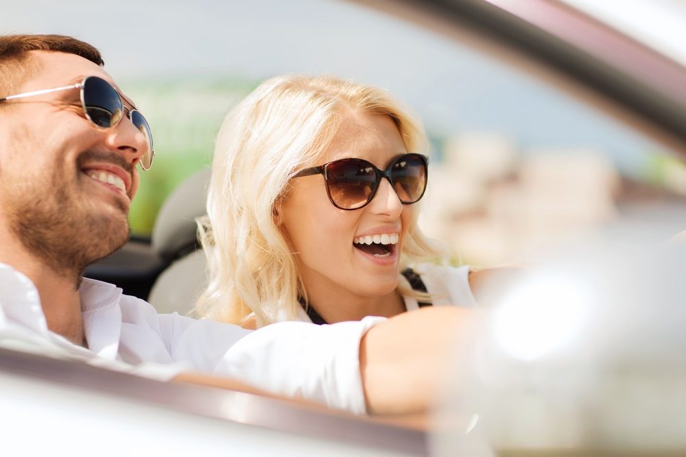 Car Loans Banner - Young couple smiling while driving in a convertible