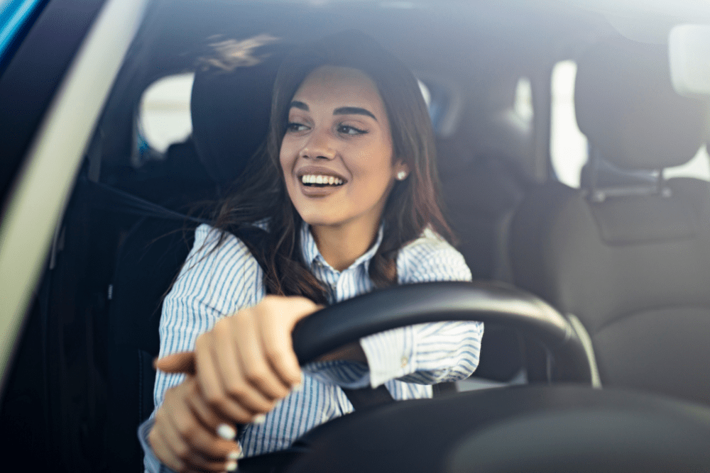 Car Loans Banner - Young woman smiling while driving her car