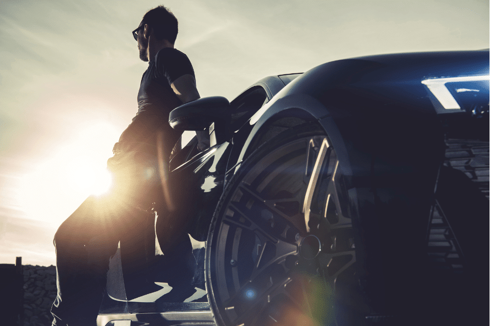 Car Loans Banner - Man standing against his luxury car looking into the sunset