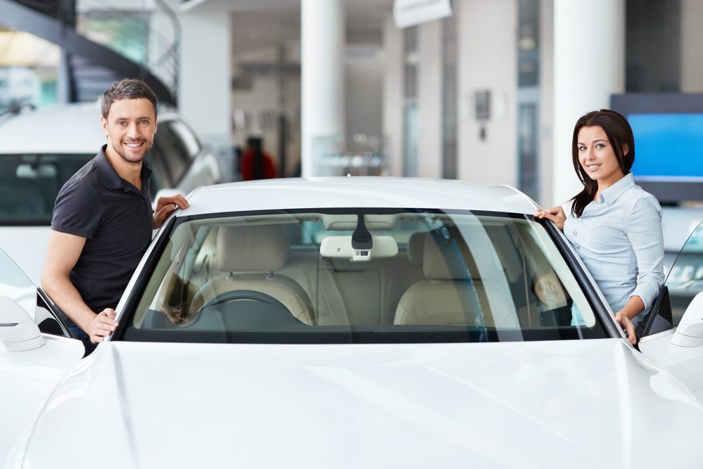 Man and woman getting into new car