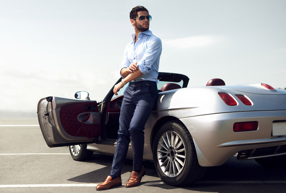 Man leaning on silver coupe sports car